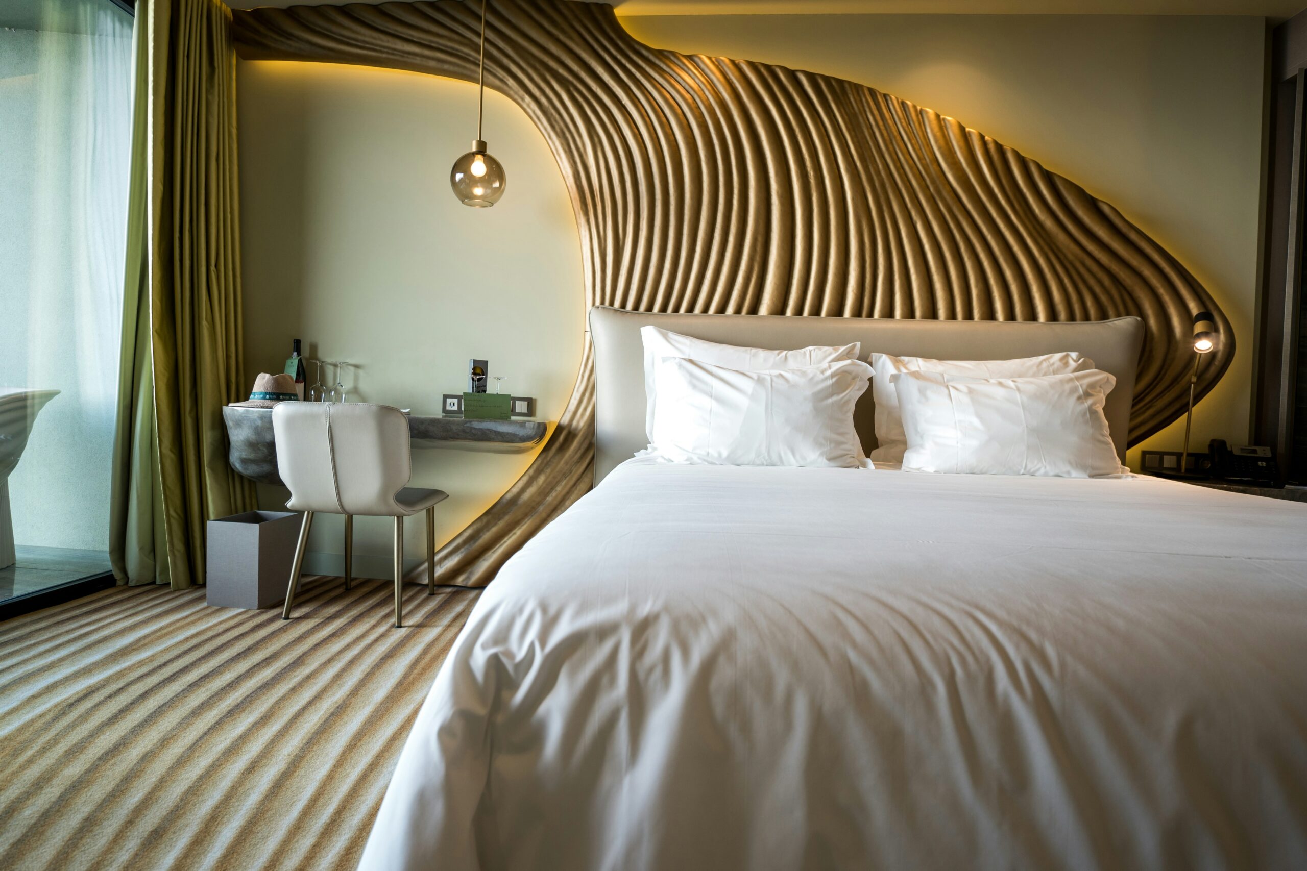 A coastal bedroom with a white bed and curved wooden slat headboard, styled with layered white bedding.A coastal bedroom with a white bed and curved wooden slat headboard, styled with layered white bedding.